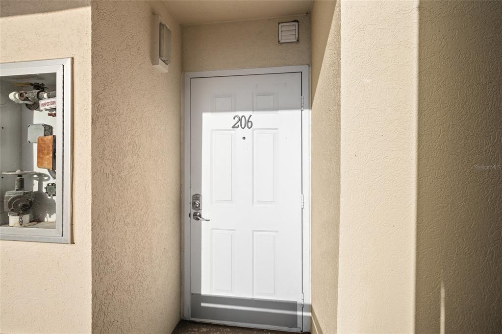 A white entry door labeled 206 is set within a beige stucco exterior wall — 2320 TERRA CEIA BAY BOULEVARD UNIT 206, PALMETTO, FL