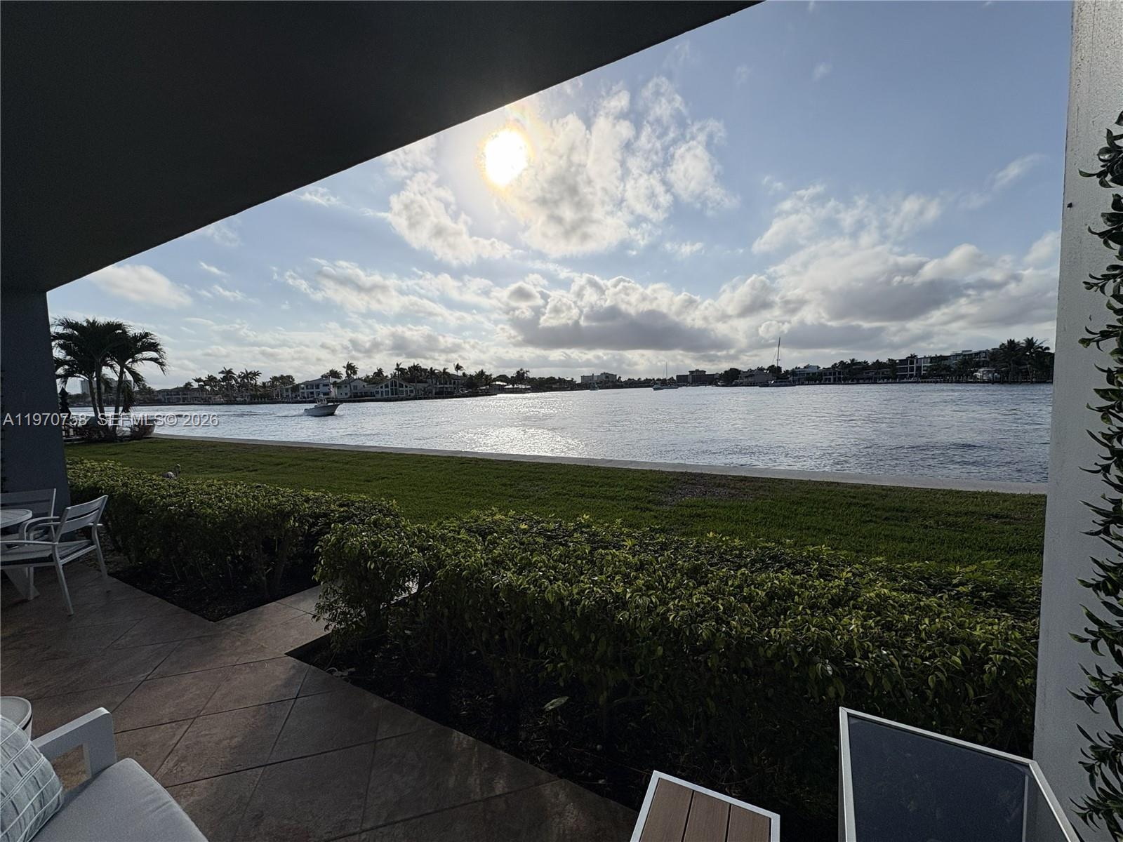 A patio overlooks a grassy lawn and a wide waterway under a sunny sky — 1201 S Riverside Dr # 107, Pompano Beach FL 33062, POMPANO BEACH, FL