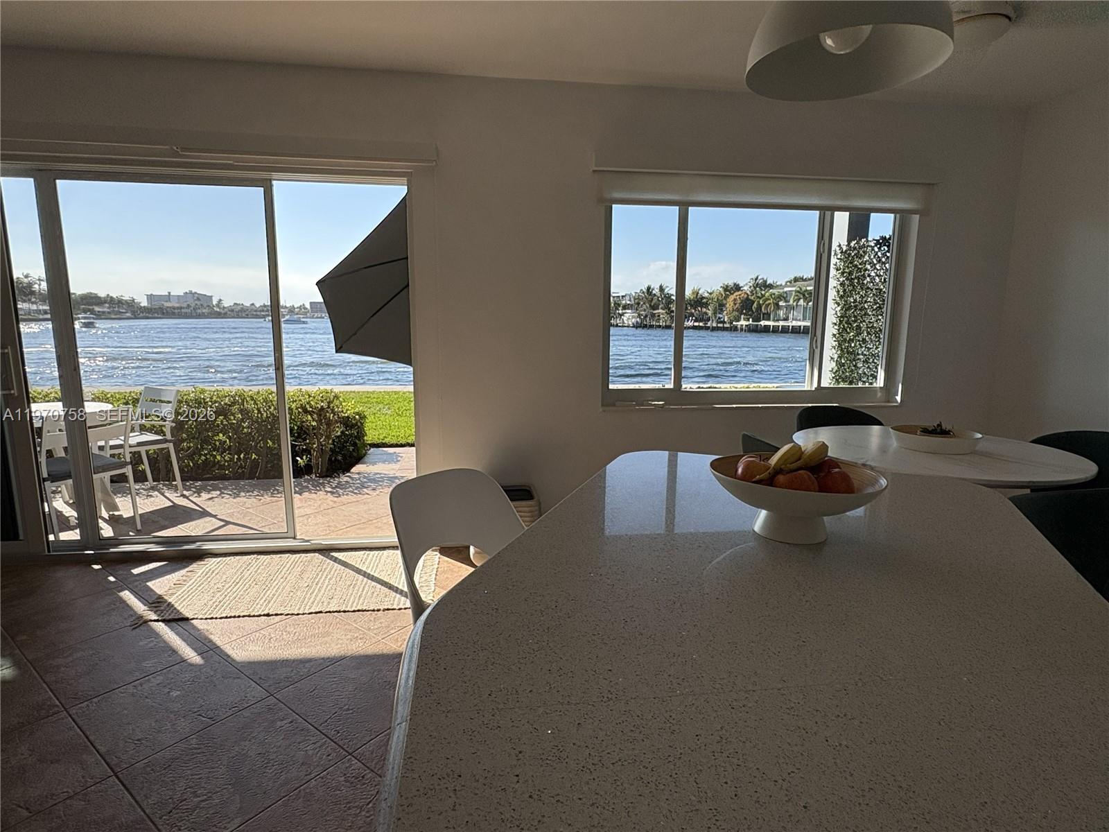 A kitchen island with a fruit bowl overlooks a waterfront patio through sliding glass doors — 1201 S Riverside Dr # 107, Pompano Beach FL 33062, POMPANO BEACH, FL