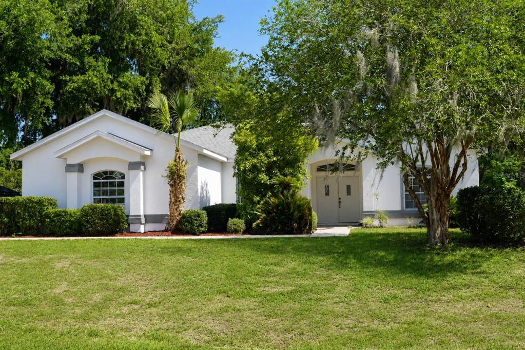A white single-story house with a front lawn, trees, and a double-door entrance — 7942 SW 103RD LOOP, OCALA, FL