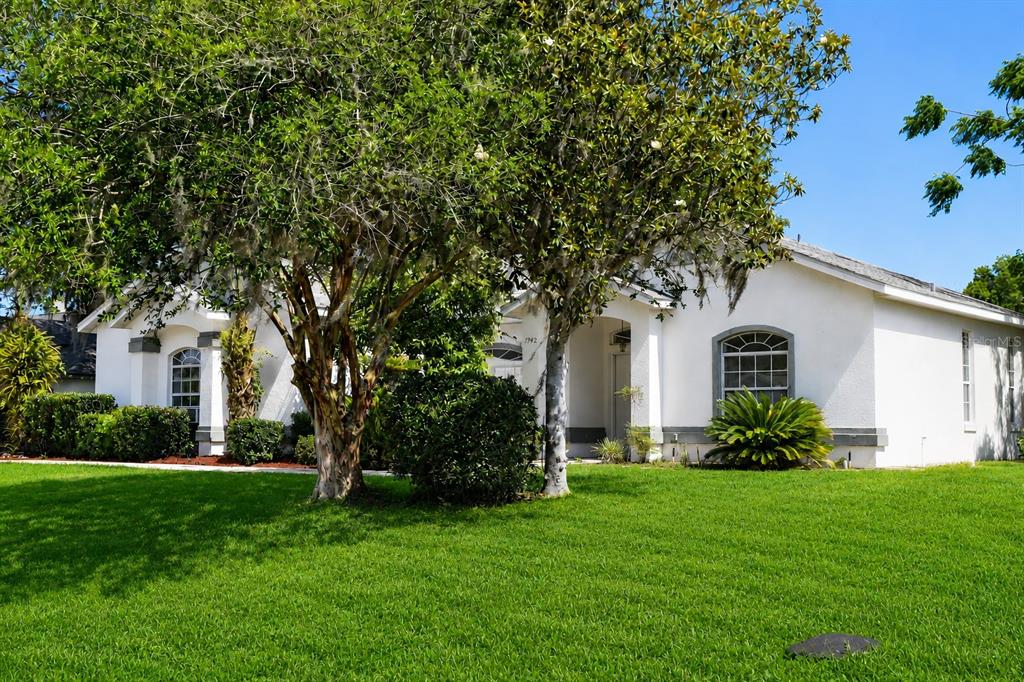 A white single-story house with a green lawn and large trees in the front yard — 7942 SW 103RD LOOP, OCALA, FL