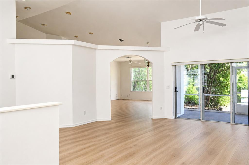 A bright living room features light wood-look flooring, a vaulted ceiling, and sliding glass doors — 7942 SW 103RD LOOP, OCALA, FL