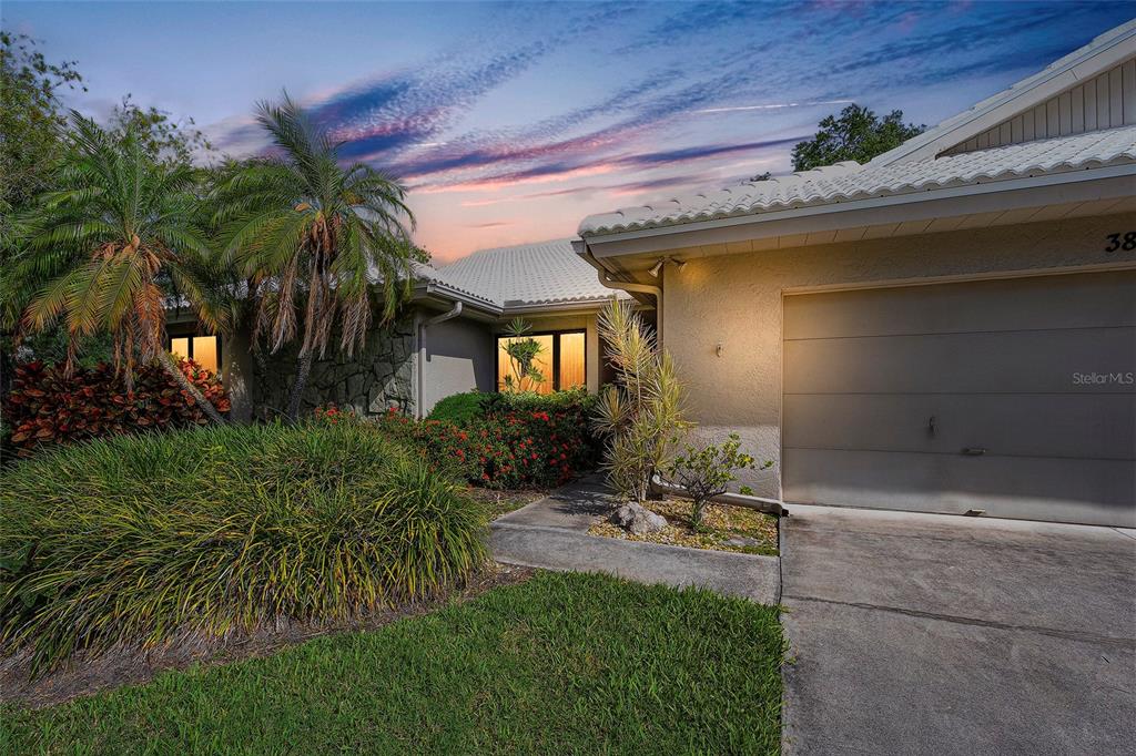 A single-story house exterior features a garage, a stone facade, and a landscaped front yard — 3825 WILSHIRE CIRCLE UNIT 1, SARASOTA, FL