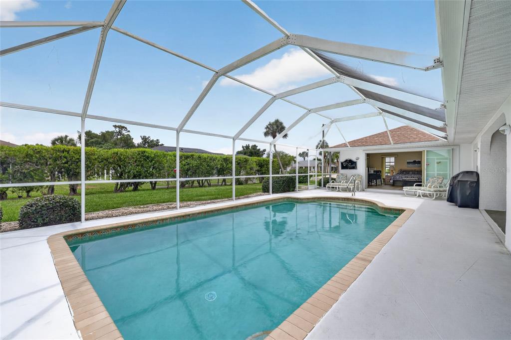 A swimming pool with a screened enclosure sits on a patio next to a house — 4236 FENWAY STREET, PORT CHARLOTTE, FL