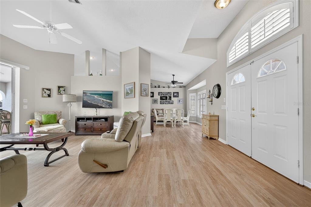 A bright living room features light wood-look flooring, a vaulted ceiling, and a double-door entrance — 4236 FENWAY STREET, PORT CHARLOTTE, FL