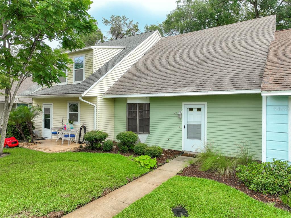 A two-story townhouse exterior features light yellow and green siding with a concrete walkway — 232 N RIDGEWOOD AVENUE UNIT G41, EDGEWATER, FL