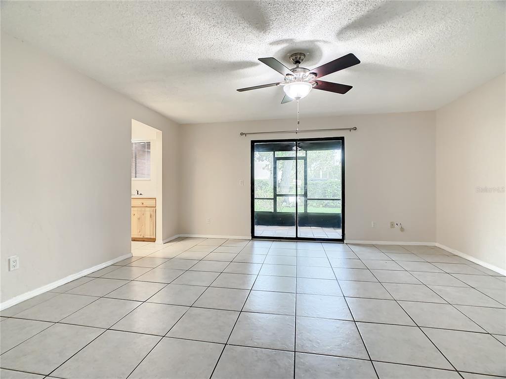 A room with light-colored floor tiles, a ceiling fan, and sliding glass doors to a patio — 232 N RIDGEWOOD AVENUE UNIT G41, EDGEWATER, FL