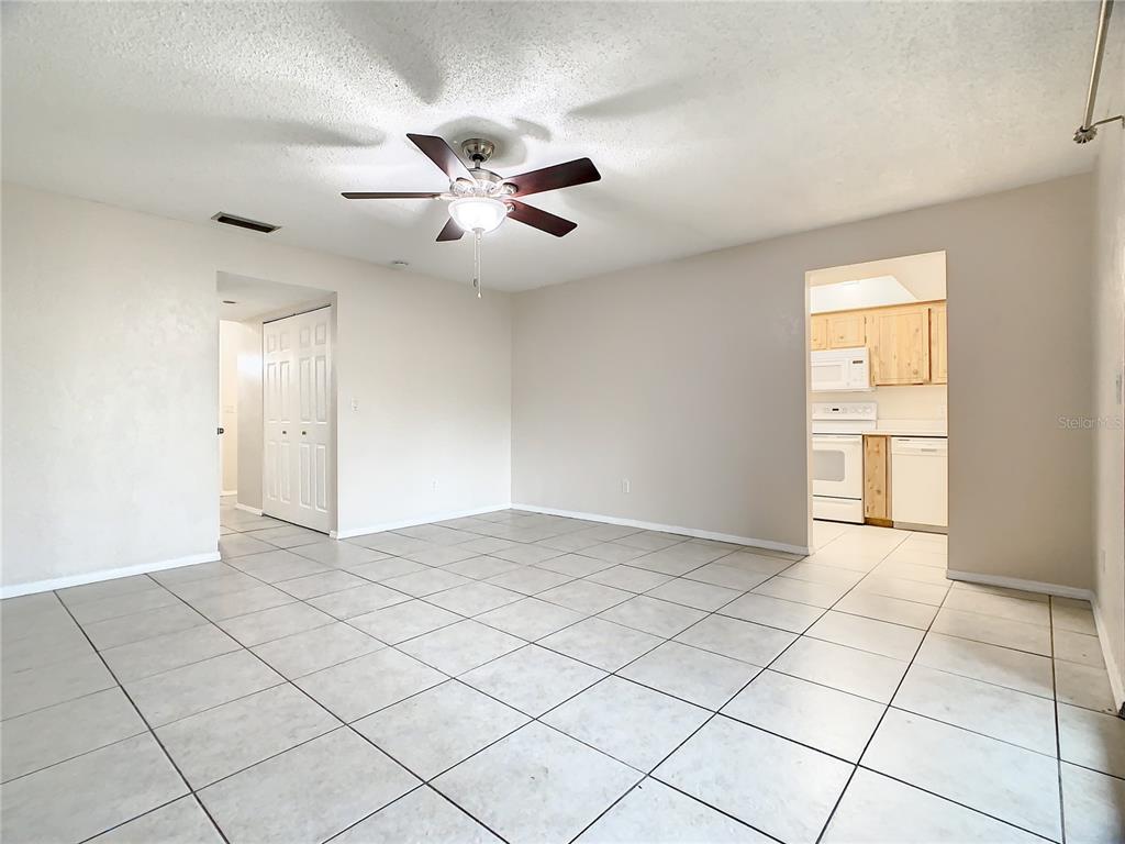 A living room with light-colored tile flooring, a ceiling fan, and an adjacent kitchen — 232 N RIDGEWOOD AVENUE UNIT G41, EDGEWATER, FL