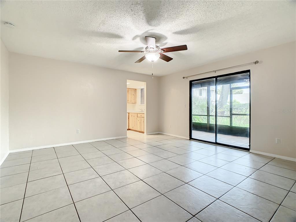 A living room with light-colored floor tiles, a ceiling fan, and sliding glass doors — 232 N RIDGEWOOD AVENUE UNIT G41, EDGEWATER, FL