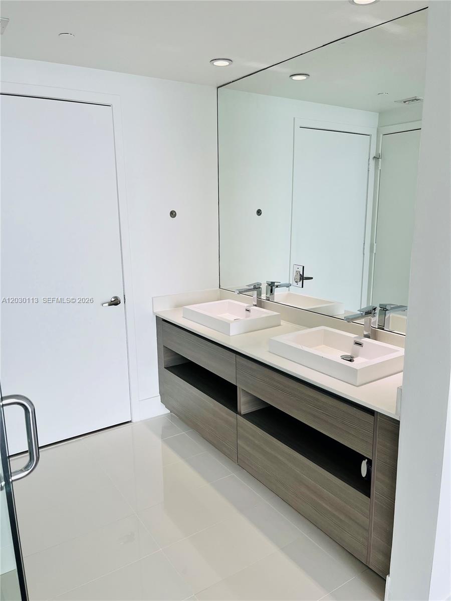 A bathroom features a double vanity with vessel sinks, wood-toned cabinetry, and a large mirror — 460 NE 28th St # 1408, Miami FL 33137, MIAMI, FL