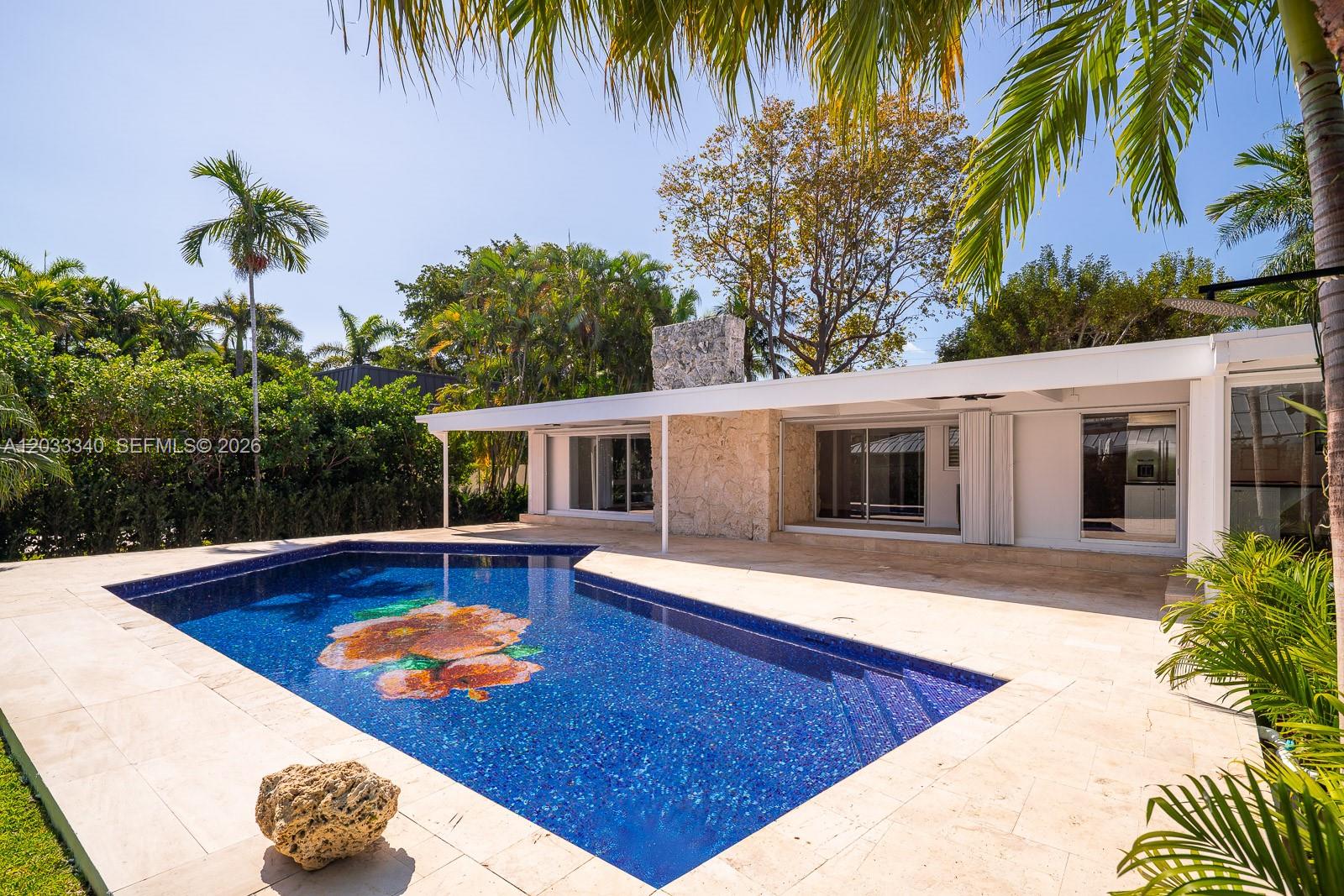 A swimming pool with a floral mosaic sits on a patio beside a modern house — 669 S Mashta Dr, Key Biscayne FL 33149, KEY BISCAYNE, FL