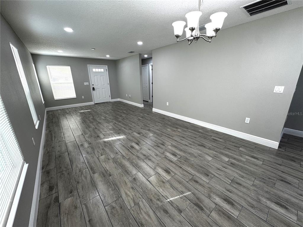 An empty room features gray walls, wood-look tile flooring, and a white chandelier — 5 OLIVE PLACE, OCALA, FL