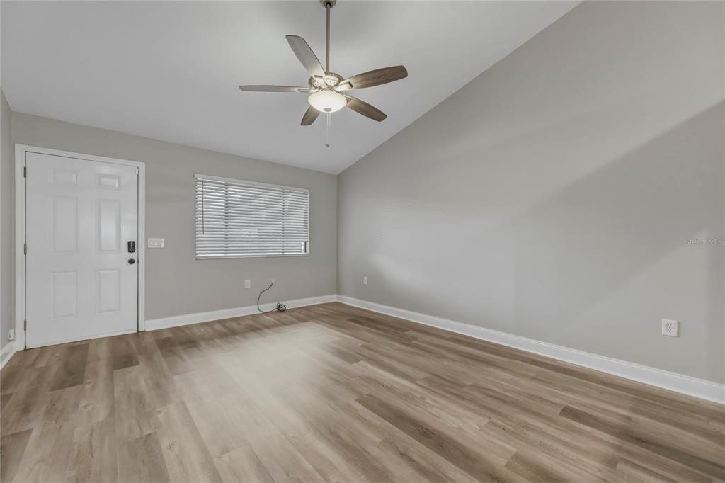 An empty room with light gray walls, wood-look flooring, a ceiling fan, and a window — 1203 SHADY PINES LANE, TITUSVILLE, FL