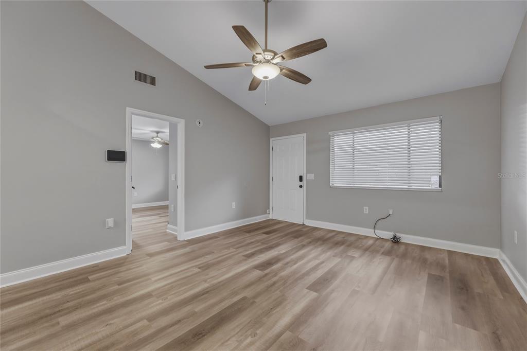 A room with light gray walls, wood-look flooring, a ceiling fan, and a white door — 1203 SHADY PINES LANE, TITUSVILLE, FL