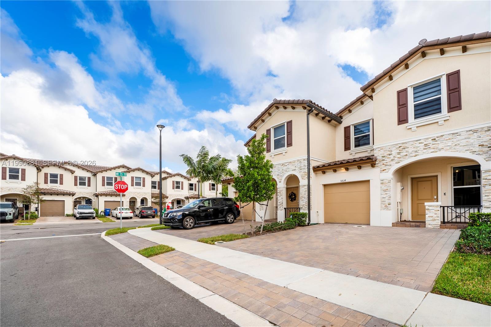 A row of two-story townhouses with beige stucco, stone accents, and paved driveways — 5514 NW 27th St, Lauderhill FL 33313, LAUDERHILL, FL