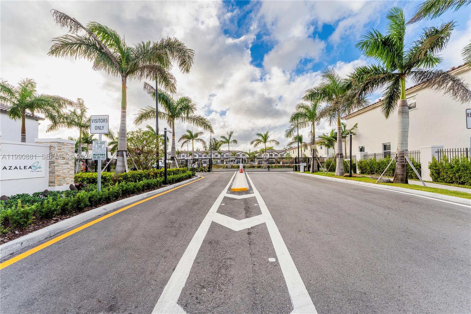 The gated entrance to a residential community features palm trees, paved roads, and signage — 5514 NW 27th St, Lauderhill FL 33313, LAUDERHILL, FL