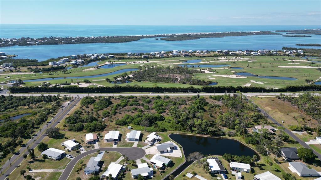 An aerial view shows a residential neighborhood, a golf course, and the ocean beyond — 6631 PLACIDA ROAD, ENGLEWOOD, FL