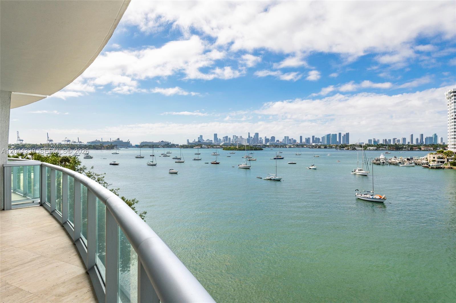A balcony with a glass railing overlooks a bay filled with sailboats and a city skyline — 1470 16th St # 401, Miami Beach FL 33139, MIAMI BEACH, FL