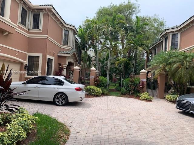 A white sedan is parked on a paved driveway in front of a multi-story townhouse complex — 2800 Kinsington Cir, Weston FL 33332, WESTON, FL