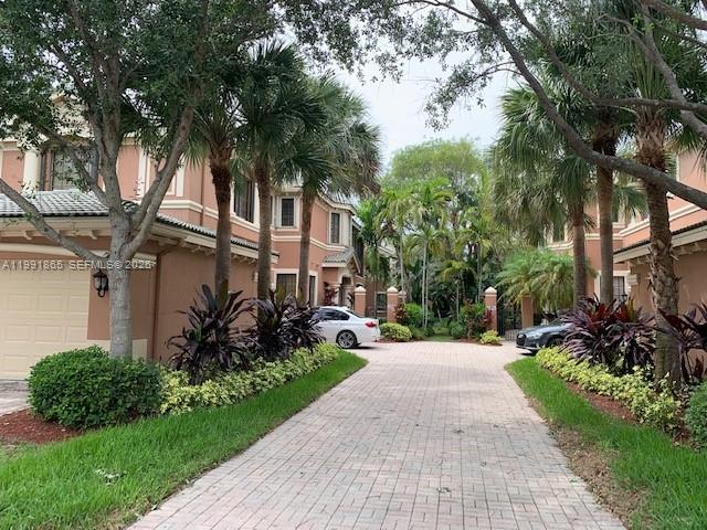 A paved driveway leads between two multi-story residential buildings surrounded by palm trees — 2800 Kinsington Cir, Weston FL 33332, WESTON, FL