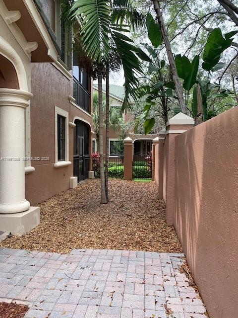 A side yard features a paved patio, gravel ground, and a tall stucco wall — 2800 Kinsington Cir, Weston FL 33332, WESTON, FL