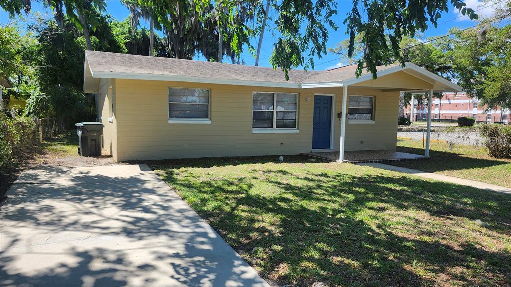 A single-story yellow house with a blue front door and a concrete driveway — 565 3RD AVENUE, DAYTONA BEACH, FL