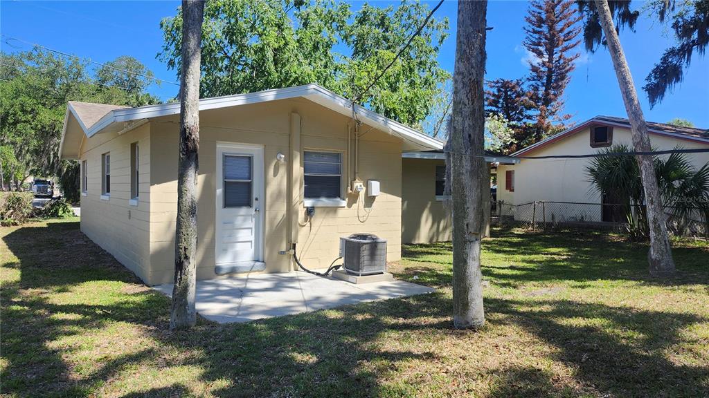The exterior of a tan concrete block house features a small patio and air conditioner — 565 3RD AVENUE, DAYTONA BEACH, FL