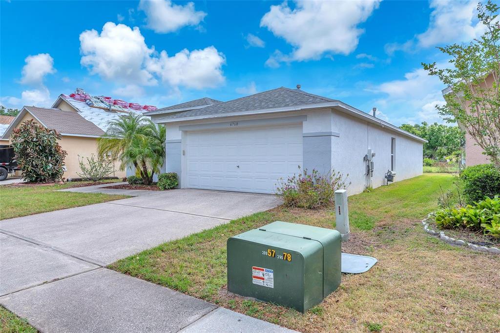 A single-story house with a white garage door and a green utility box in front — 6760 WATERTON DRIVE, RIVERVIEW, FL