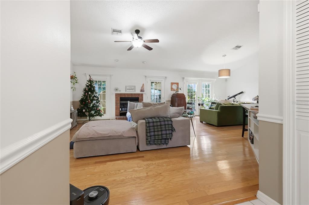 A spacious living room features hardwood floors, a brick fireplace, and a large sectional sofa — 905 NORTHERN OAKS TERRACE, DELAND, FL