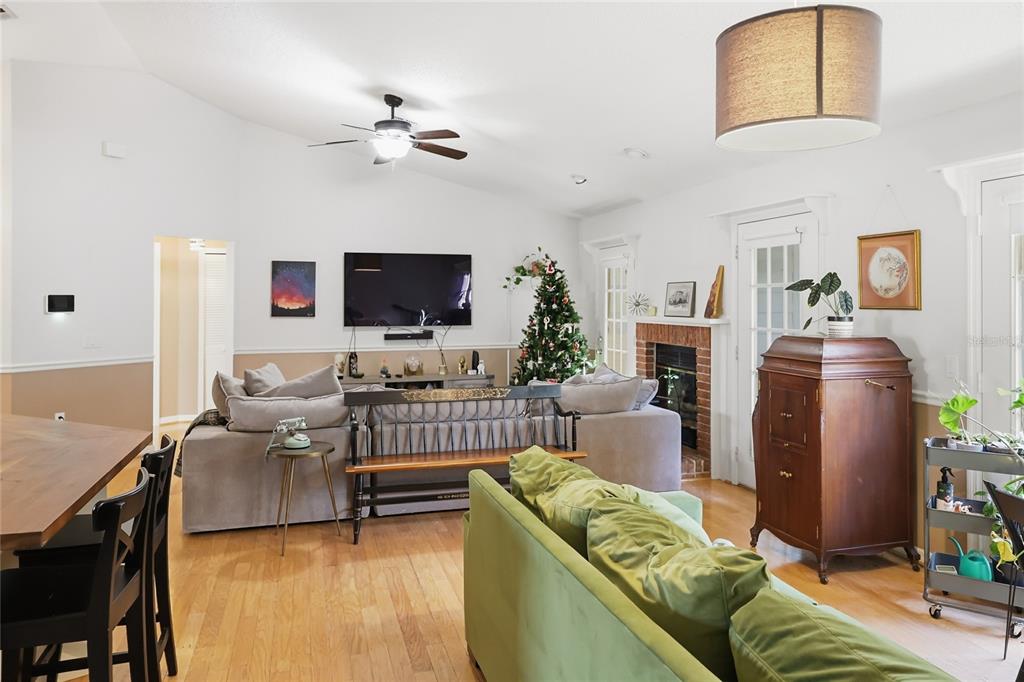 A living room features a vaulted ceiling, hardwood floors, a fireplace, and two sofas — 905 NORTHERN OAKS TERRACE, DELAND, FL