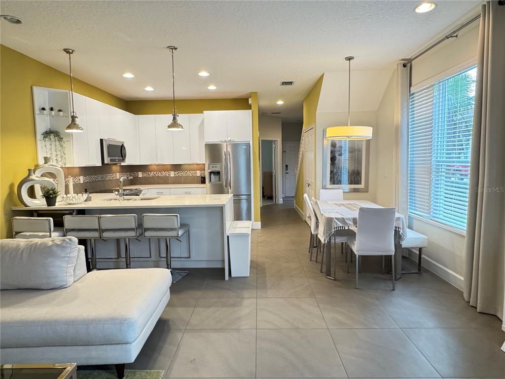 A modern kitchen with white cabinets, stainless steel appliances, and an adjacent dining area — 17343 SERENIDAD BLVD, CLERMONT, FL