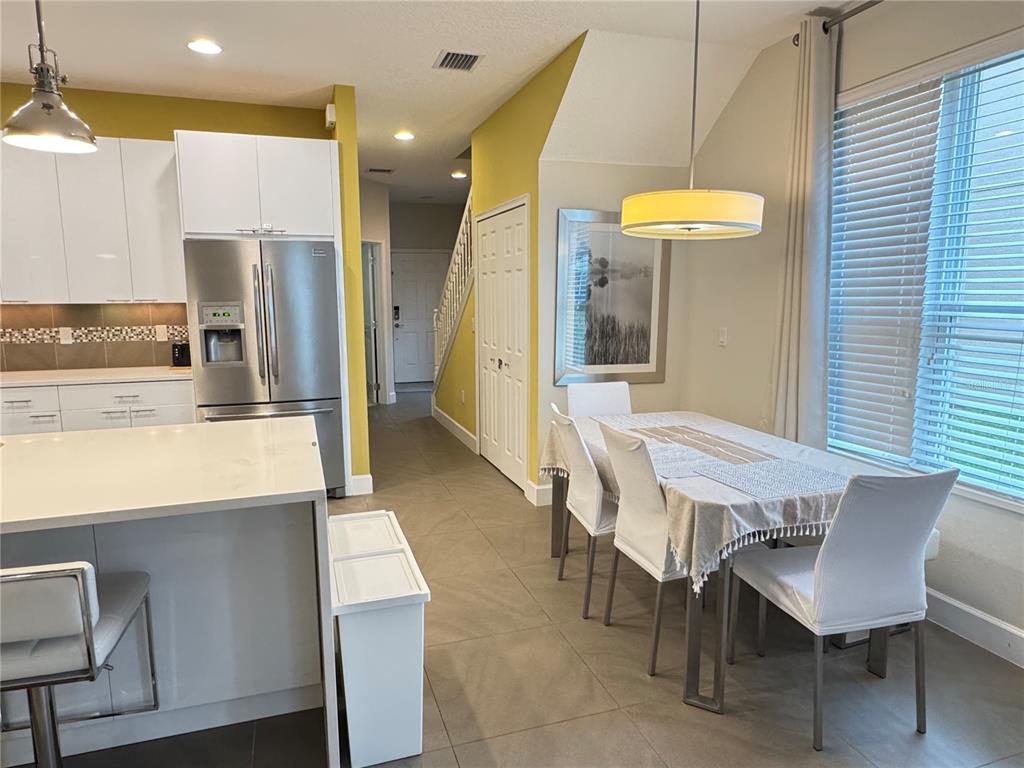 A kitchen and dining area with white cabinets, stainless steel appliances, and tile flooring — 17343 SERENIDAD BLVD, CLERMONT, FL