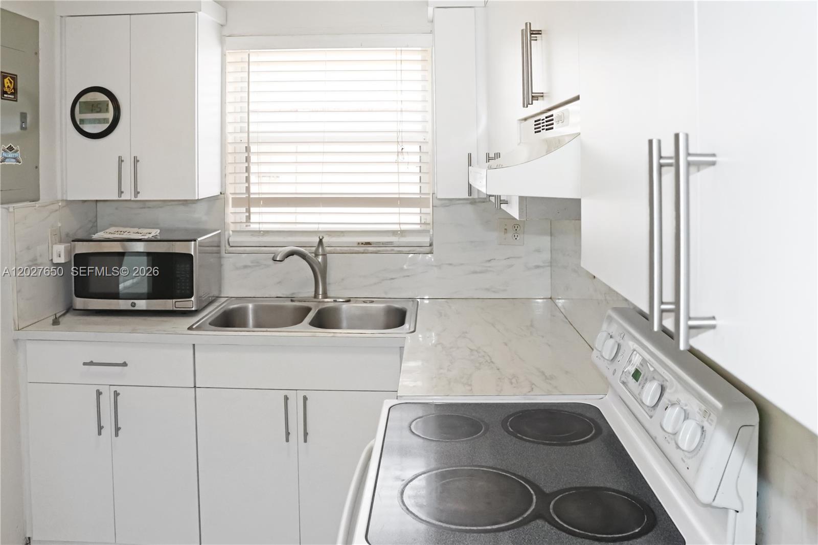 A kitchen features white cabinets, a stainless steel sink, a microwave, and a glass-top stove — 15006 SW 80th Ter # 913, Miami FL 33193, MIAMI, FL