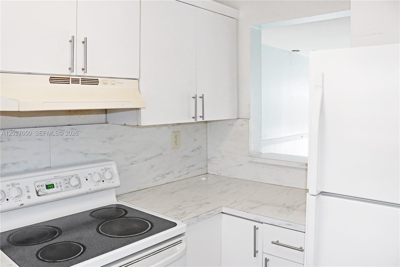 A white kitchen features a stove, marble-patterned countertops, and upper and lower cabinets — 15006 SW 80th Ter # 913, Miami FL 33193, MIAMI, FL