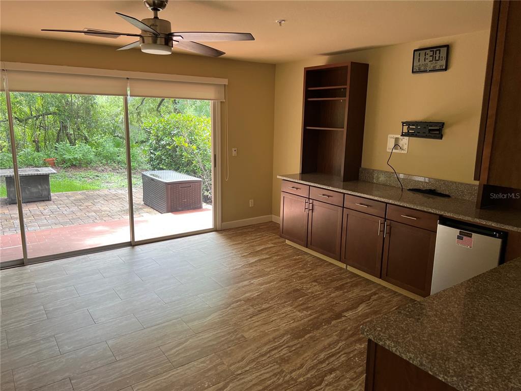 A dining area features tile flooring, dark wood cabinetry, and a sliding glass door to a patio — 1383 CURLEW ROAD, DUNEDIN, FL
