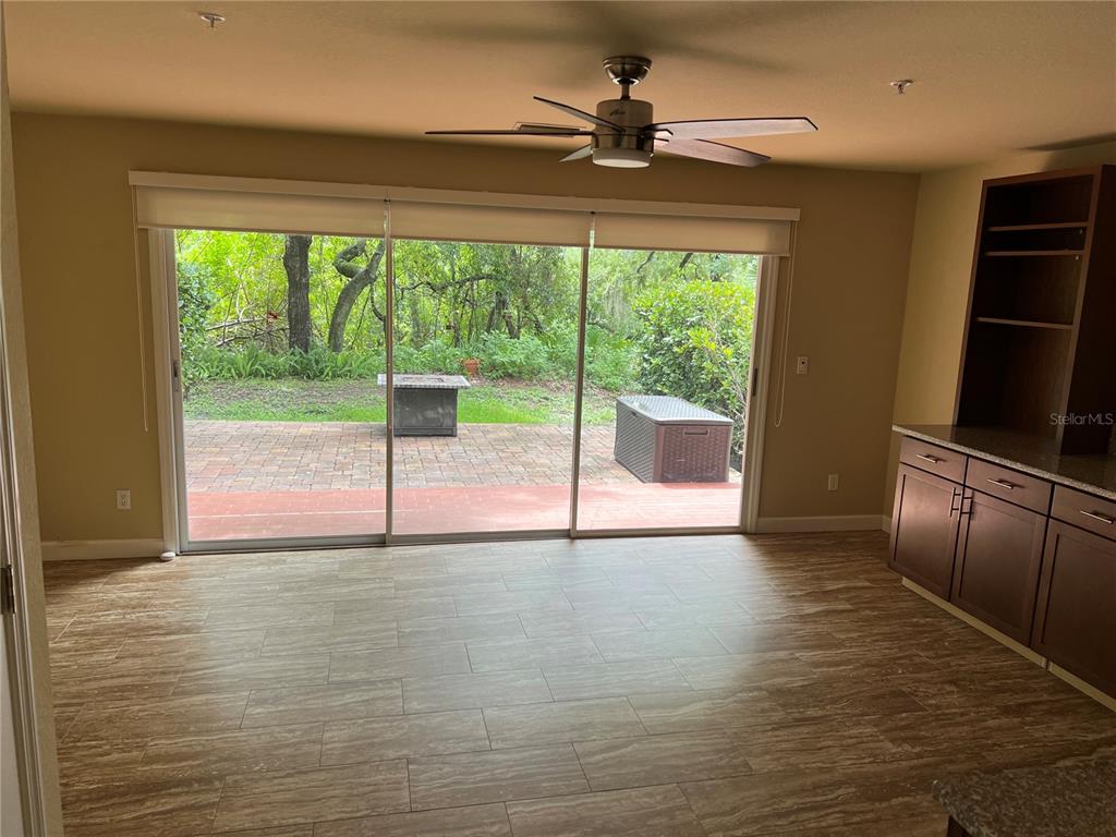 A room with wood-look tile flooring, a ceiling fan, and sliding glass doors to a patio — 1383 CURLEW ROAD, DUNEDIN, FL