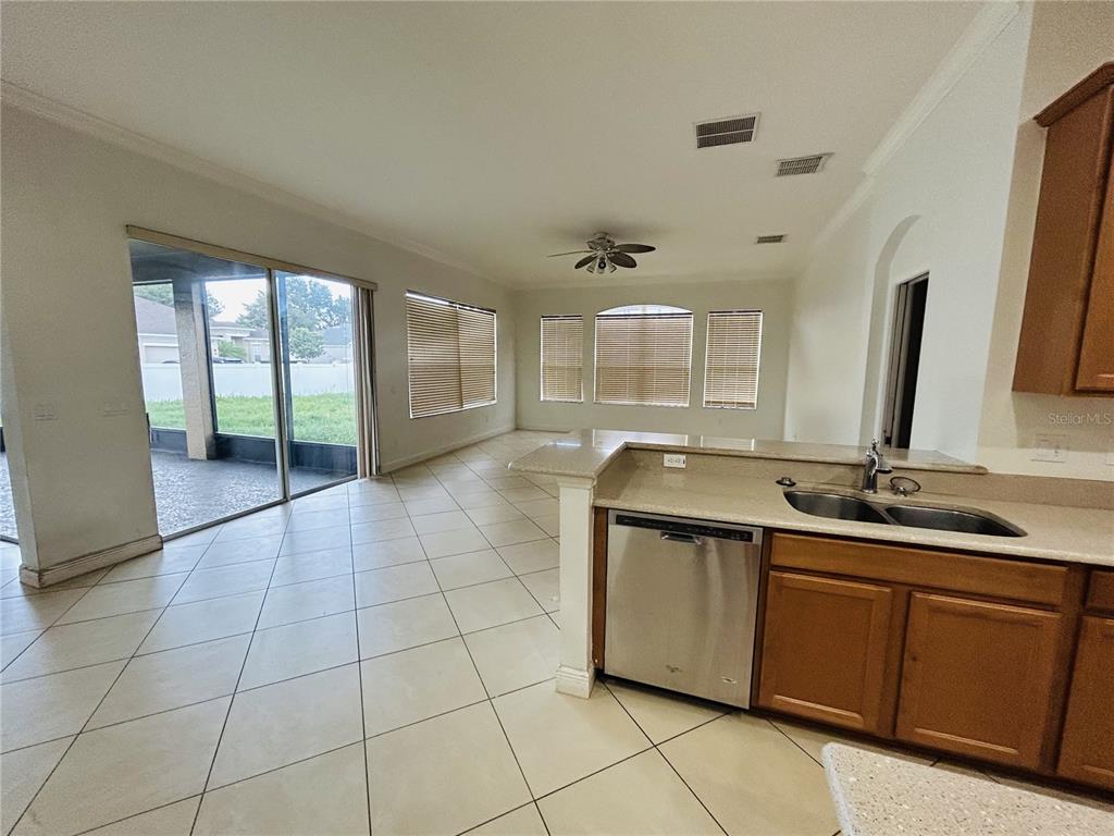 A tan single-story house with a brick paver driveway and a three-car garage — 1642 CHANDELLE LANE, WINTER GARDEN, FL