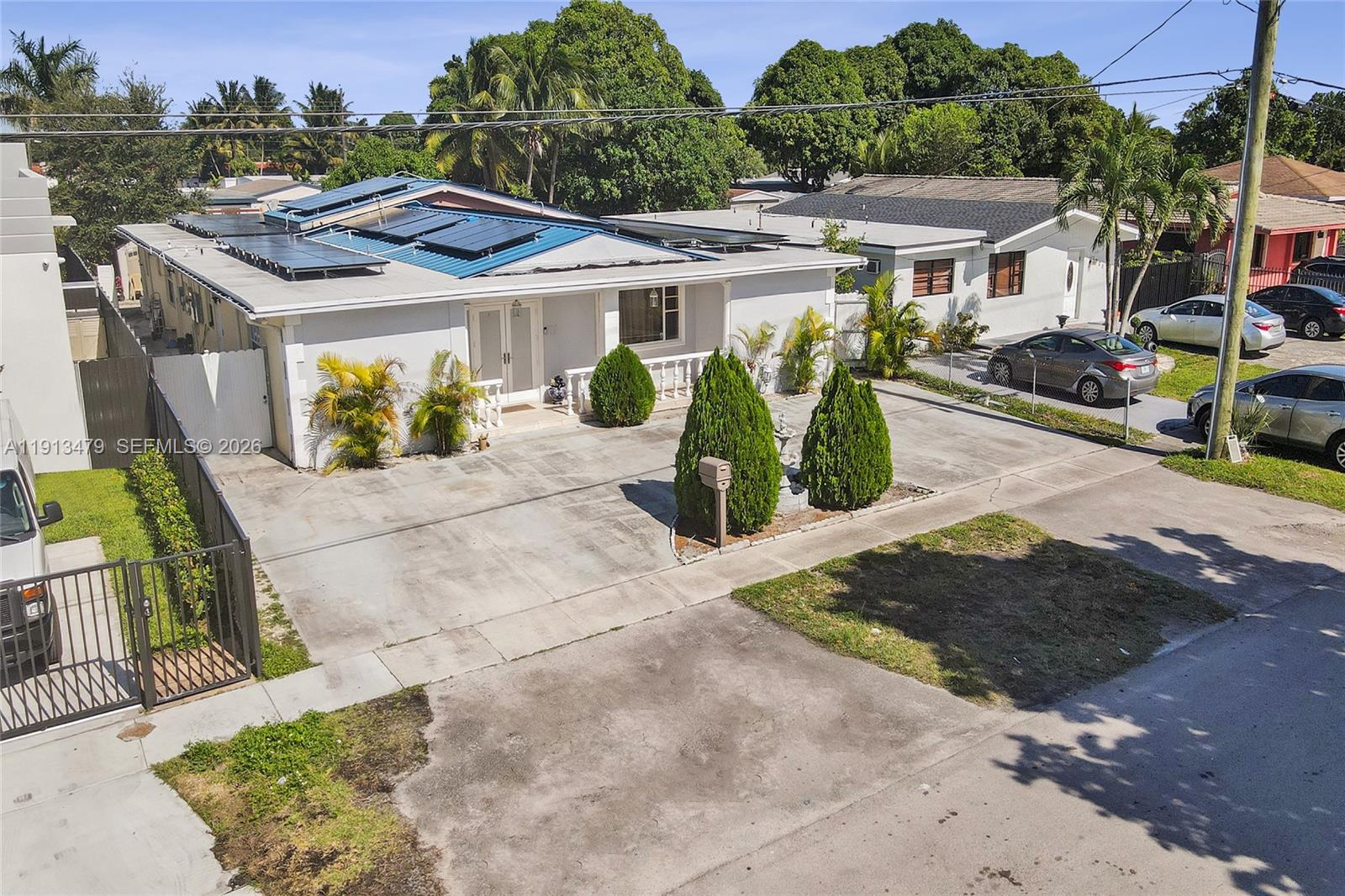 An exterior view of a single-story house with solar panels on the roof — 311 E 51st St, Hialeah FL 33013, HIALEAH, FL