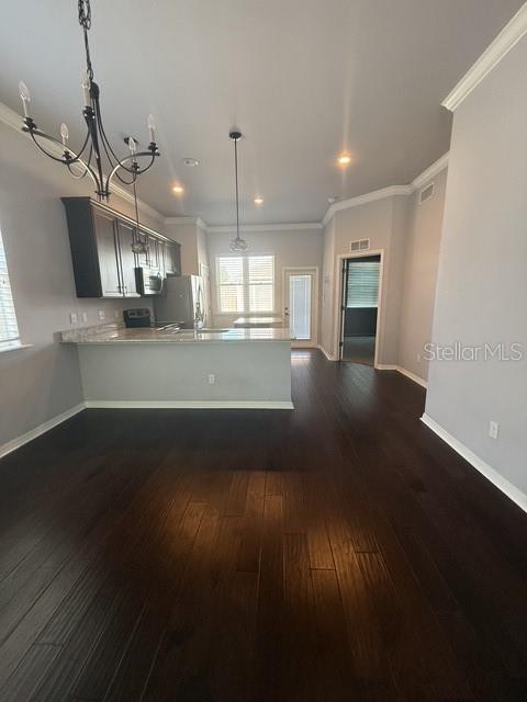 A kitchen with dark cabinets and a breakfast bar overlooks a room with dark flooring — 7925 SW 82ND DRIVE, GAINESVILLE, FL