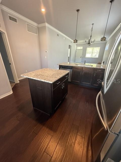 A kitchen features dark wood cabinets, granite countertops, a center island, and hardwood flooring — 7925 SW 82ND DRIVE, GAINESVILLE, FL