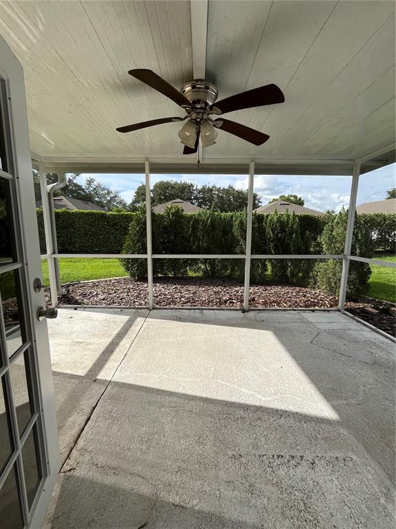 A screened-in concrete patio features a ceiling fan and views of a landscaped backyard — 2160 SUNSTONE DRIVE, LAKELAND, FL