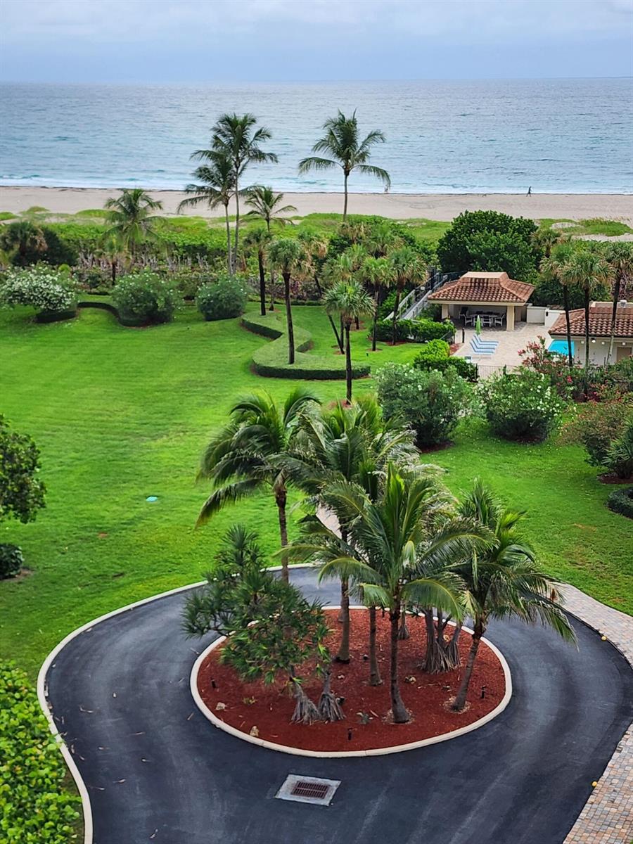 An aerial view of a circular driveway, lush green lawn, palm trees, and a beach — 3400 N Ocean Drive # 703, Riviera Beach FL 33404, RIVIERA BEACH, FL