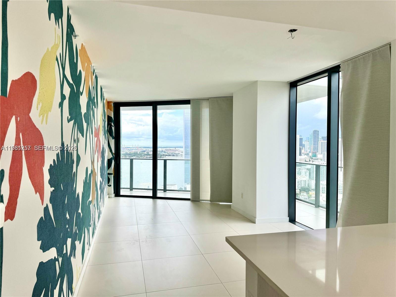 An interior room features a floral accent wall, tile flooring, and floor-to-ceiling windows with views — 501 NE 31st St # 3208, Miami FL 33137, MIAMI, FL