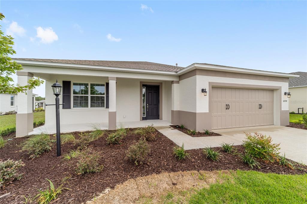 A single-story house with a white stucco exterior, a two-car garage, and a covered porch — 10354 SW 105TH TERRACE, OCALA, FL