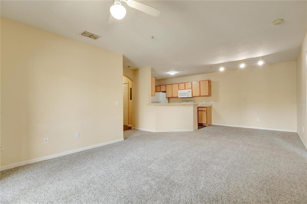 An open-concept living room with gray carpeting leads to a kitchen with light wood cabinets — 6566 SWISSCO DRIVE UNIT 425, ORLANDO, FL