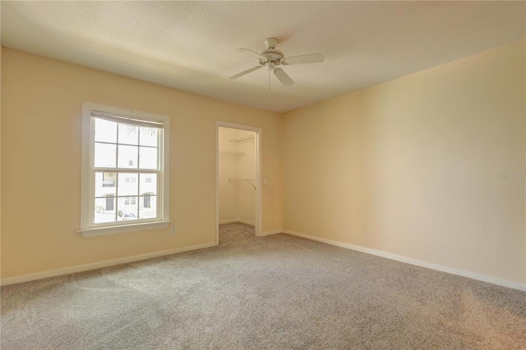 An empty bedroom features beige walls, gray carpeting, a ceiling fan, and a walk-in closet — 6566 SWISSCO DRIVE UNIT 425, ORLANDO, FL