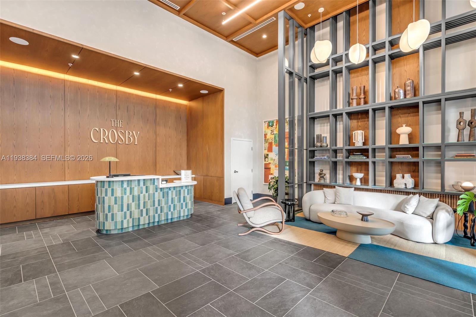 A modern lobby features a reception desk, a curved sofa, and tall decorative shelving — 11 NE 6th Street # 1607, Miami FL 33132, MIAMI, FL