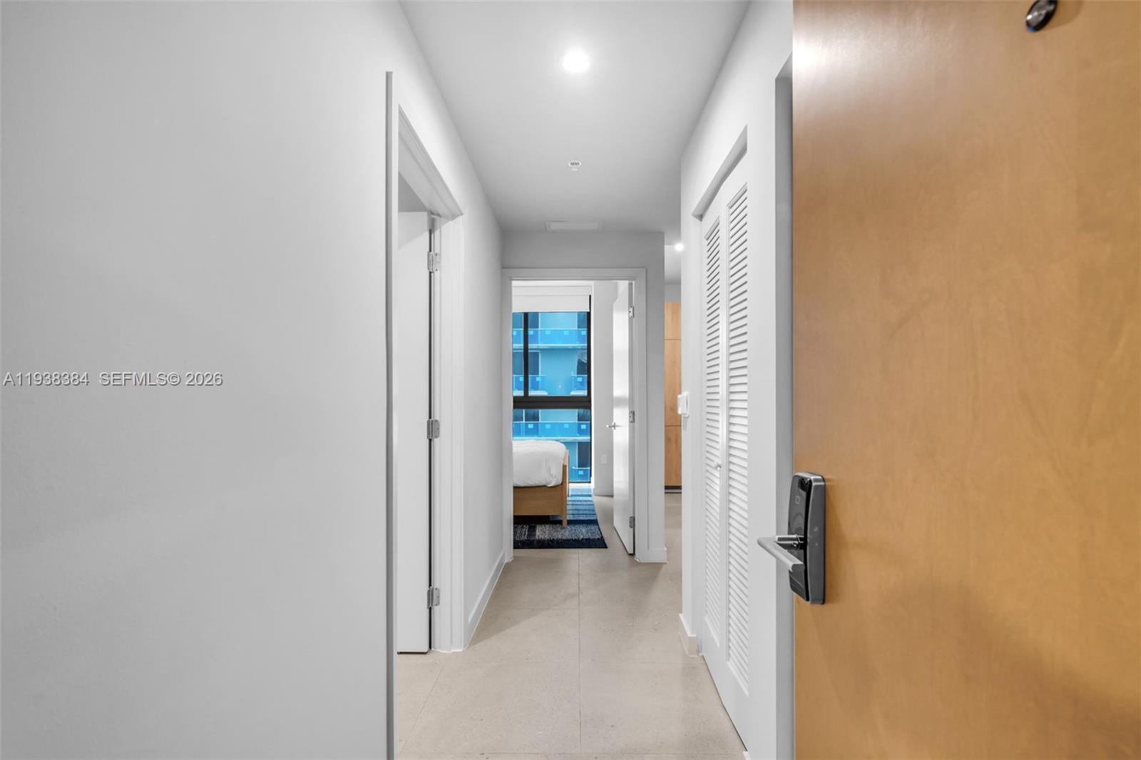 A hallway with light tile flooring leads to a bedroom with a view — 11 NE 6th Street # 1607, Miami FL 33132, MIAMI, FL