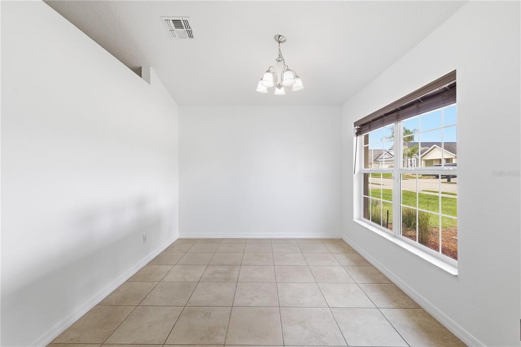 A dining room with white walls, tile flooring, a chandelier, and a large window — 248 VICTORY AVENUE, DAVENPORT, FL