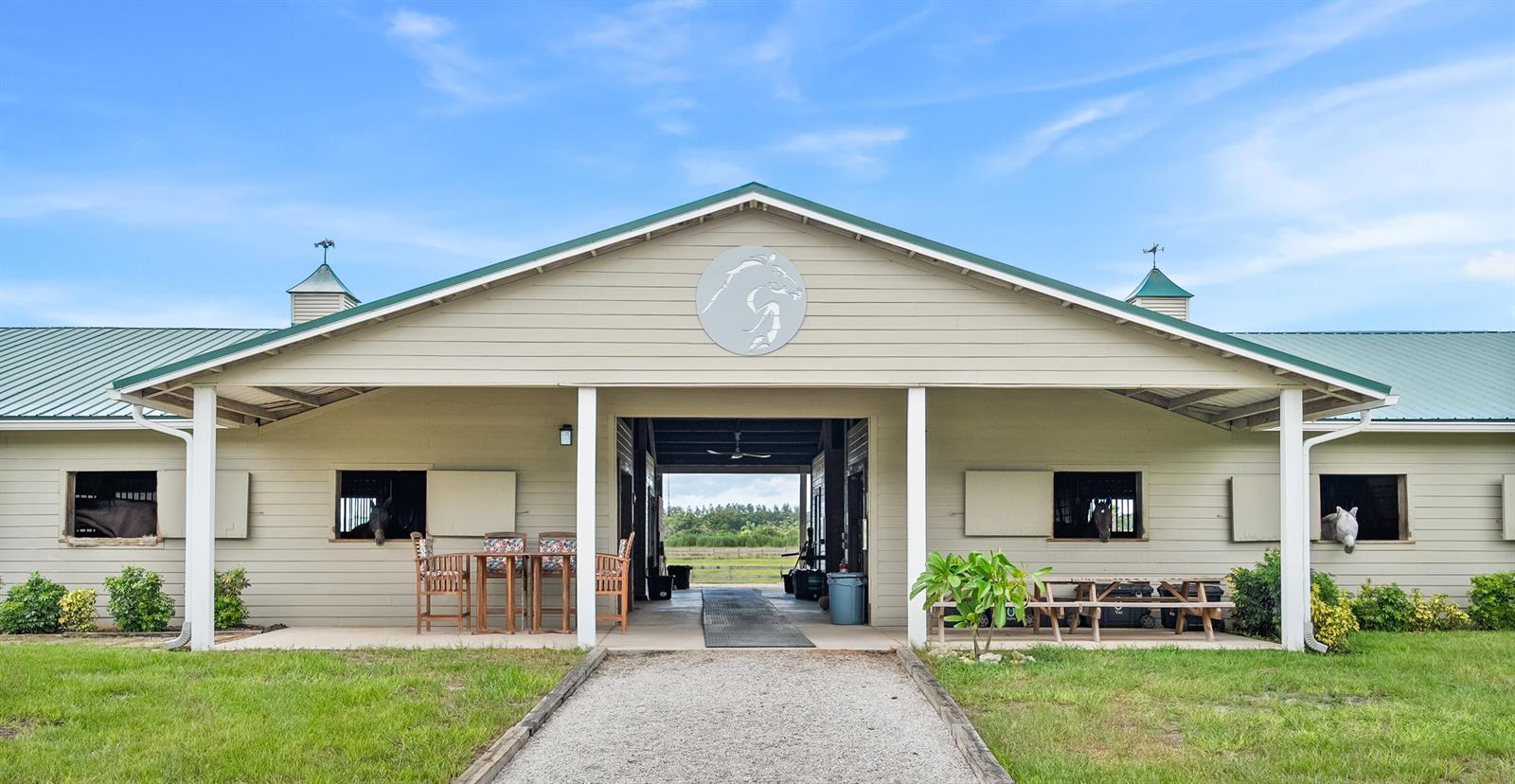 A tan horse stable with a green metal roof and a central walkway — 13700 SW Groveside Drive, Stuart FL 34997, STUART, FL